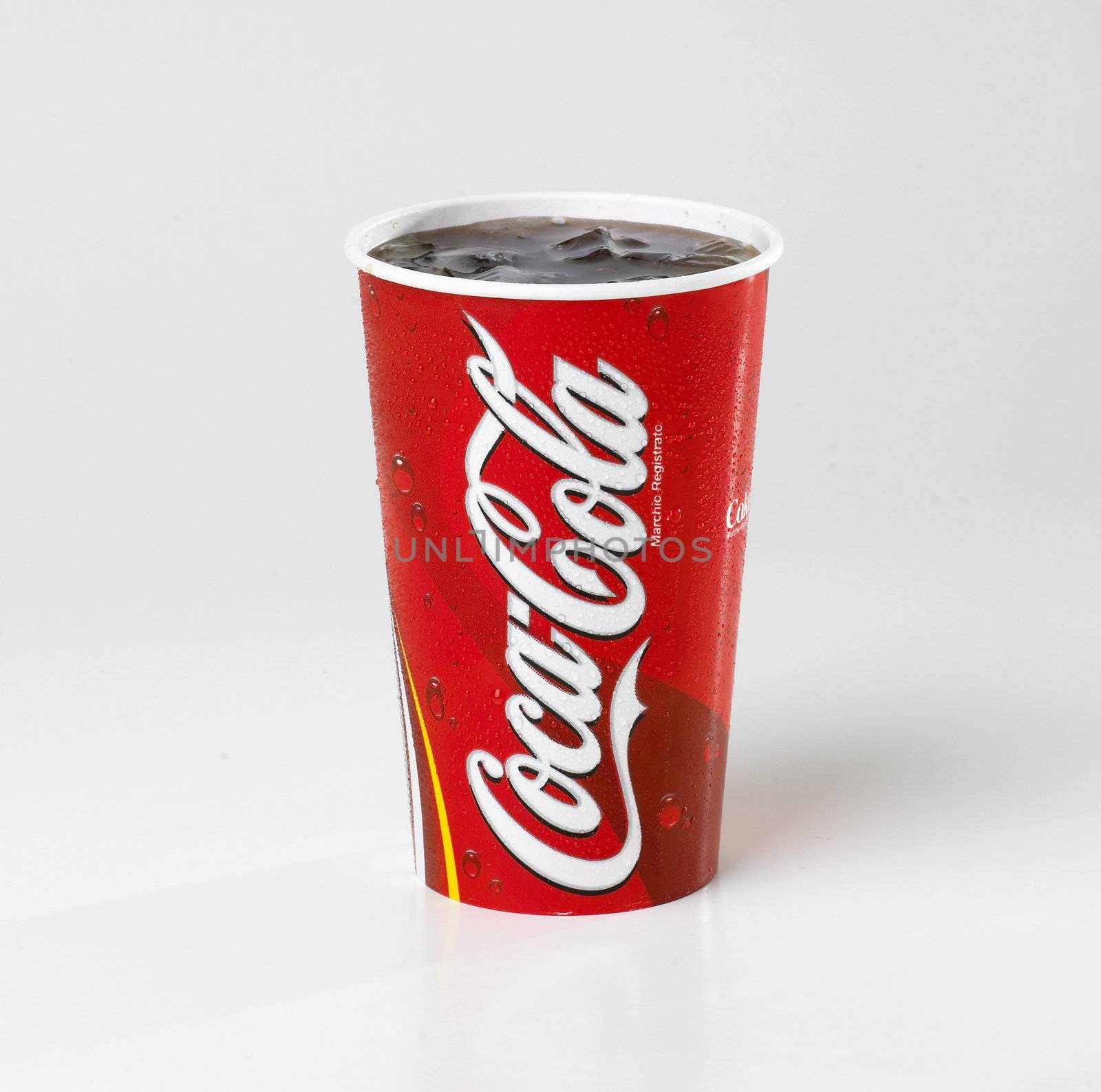 A Coca Cola  cup isolated on a white background with condensation on the cup.