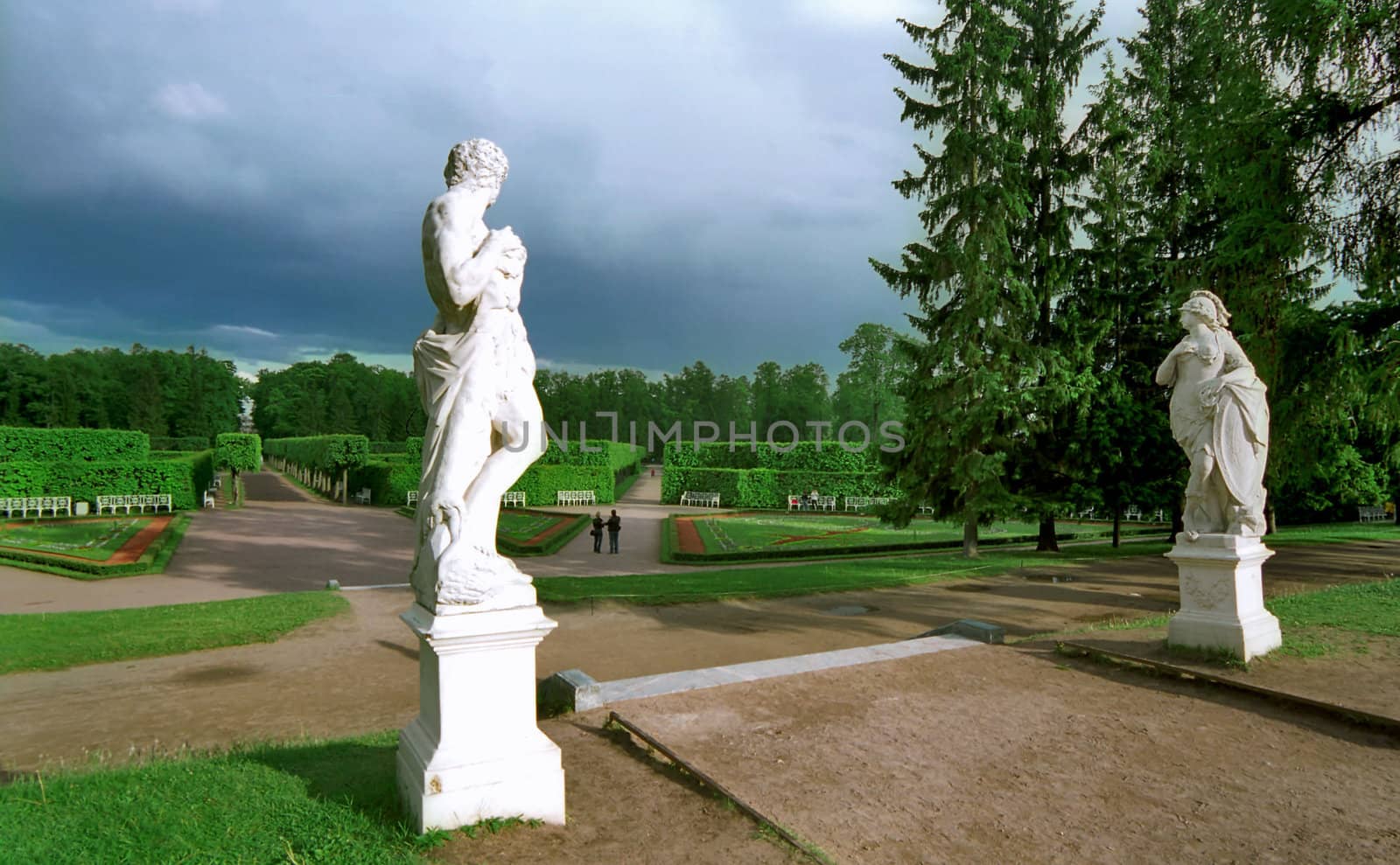 Classical statues in park looking at man and woman