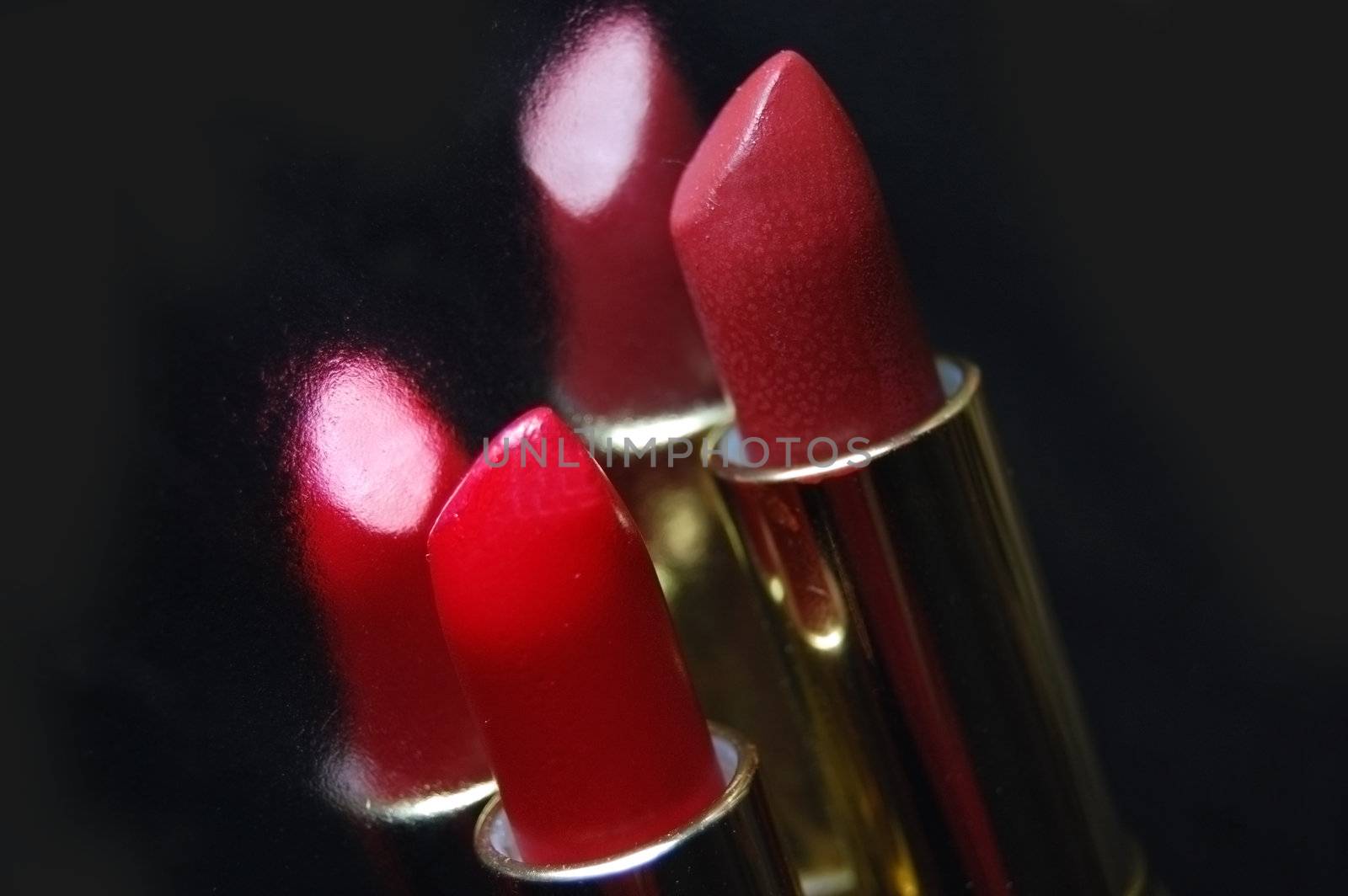 Two lipsticks with its reflection on black