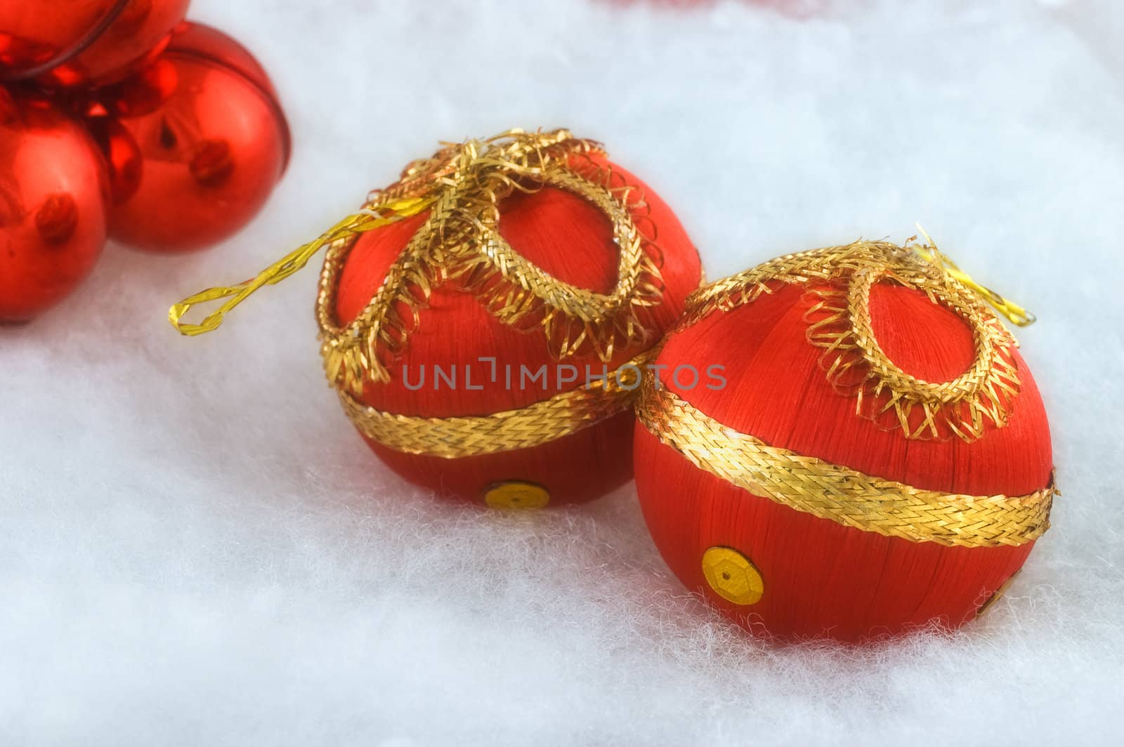 Red Christmas baubles on fluffy white background with selective focus and slight glow filter