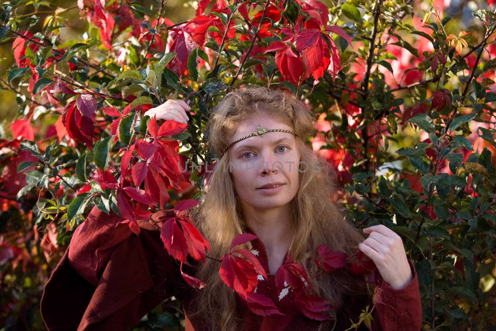 The blonde girle in medieval red dress in the autumn forest
