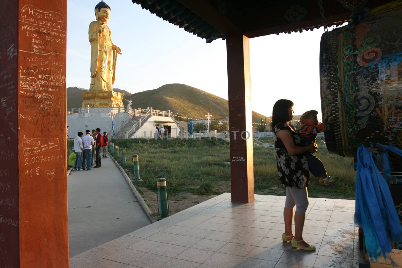 Woman take care a boy on her hand in front of Buddha statue. Ulan Bator . Mongolia. 2008
