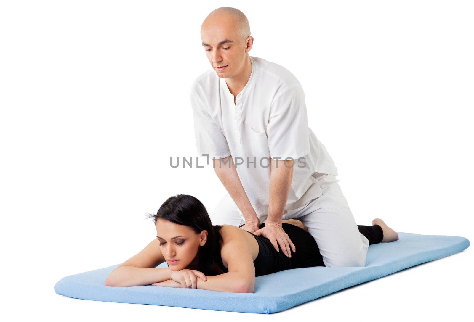 Woman lying on mat receiving massage from thai therapist, isolated on white