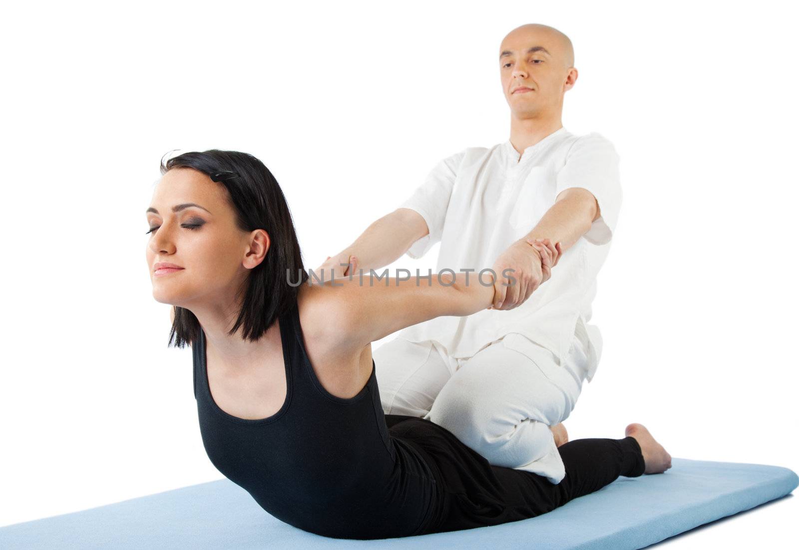 Young female receiving massage by therapist in traditional thai position