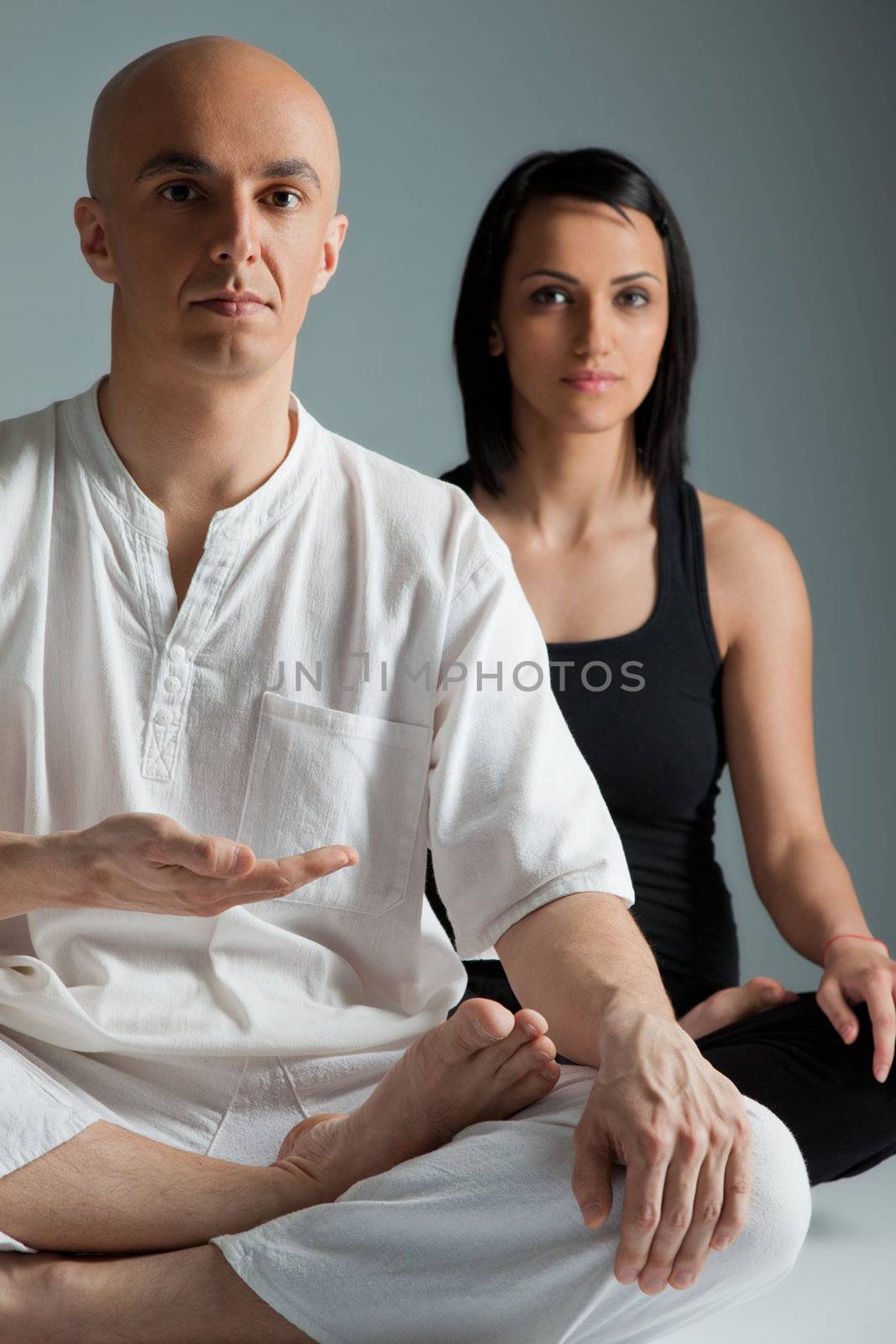 Man in white and woman in black doing yoga exercise, male on focus