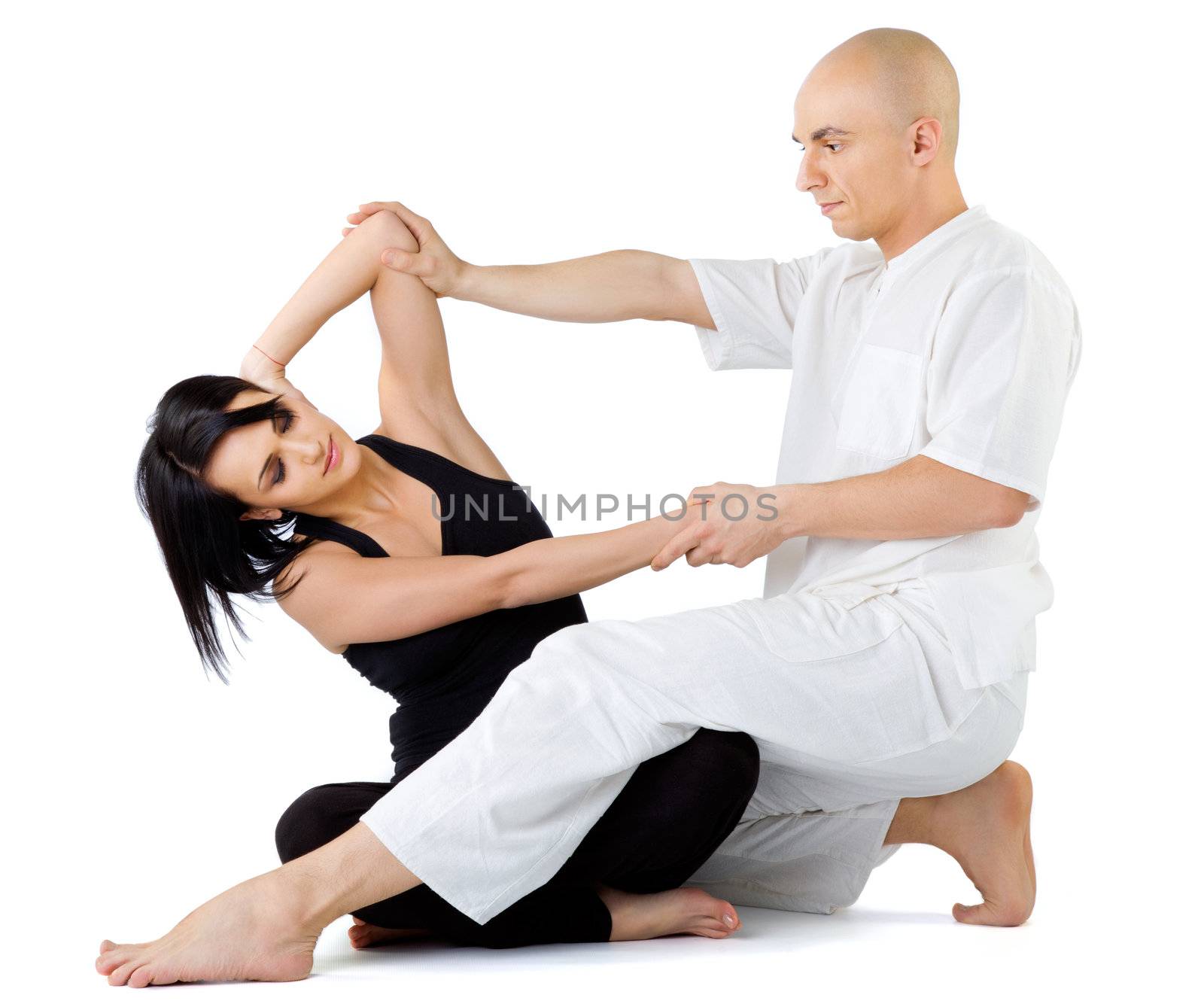 Young female sitting and receiving traditional thai arm stretching massage by therapist, isolated on white