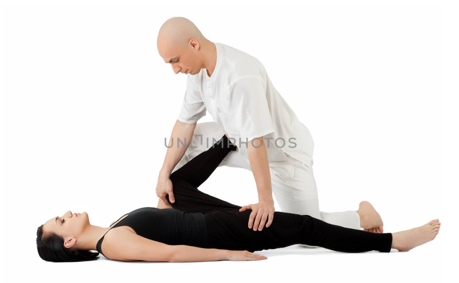 Young female lying and receiving traditional thai massage by therapist on her legs