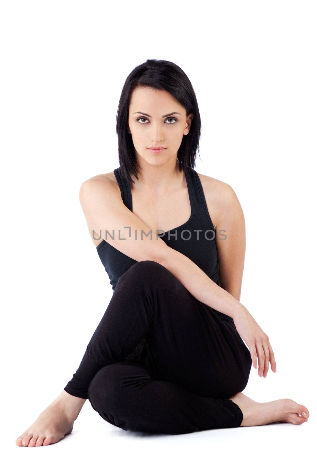 female sitting with legs crossed doing exercise, looking at camera