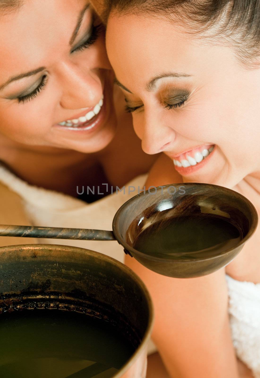 Close-up of two happy females enjoying aroma therapy in sauna and laughing