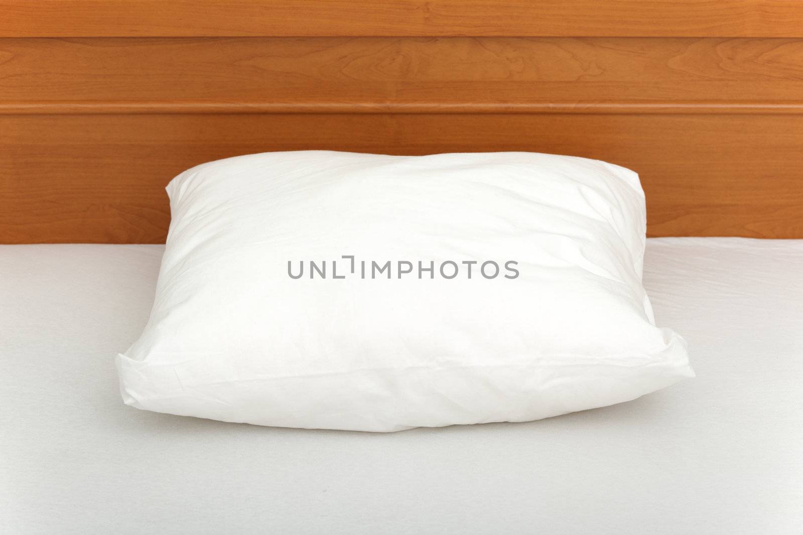 Picture of a pillow lying in an empty bed.