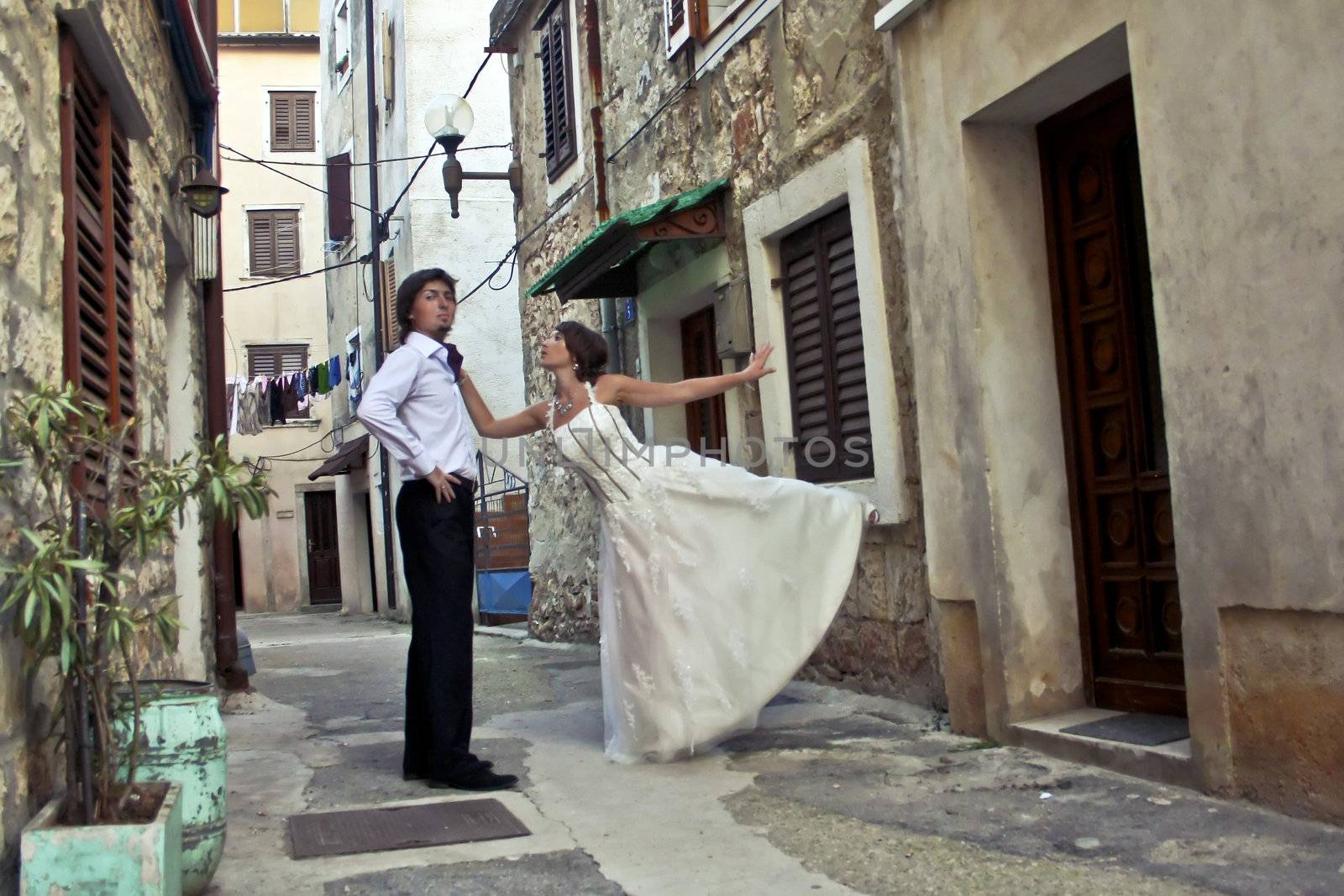 Bride asks groom come in the house on a small street of the old town