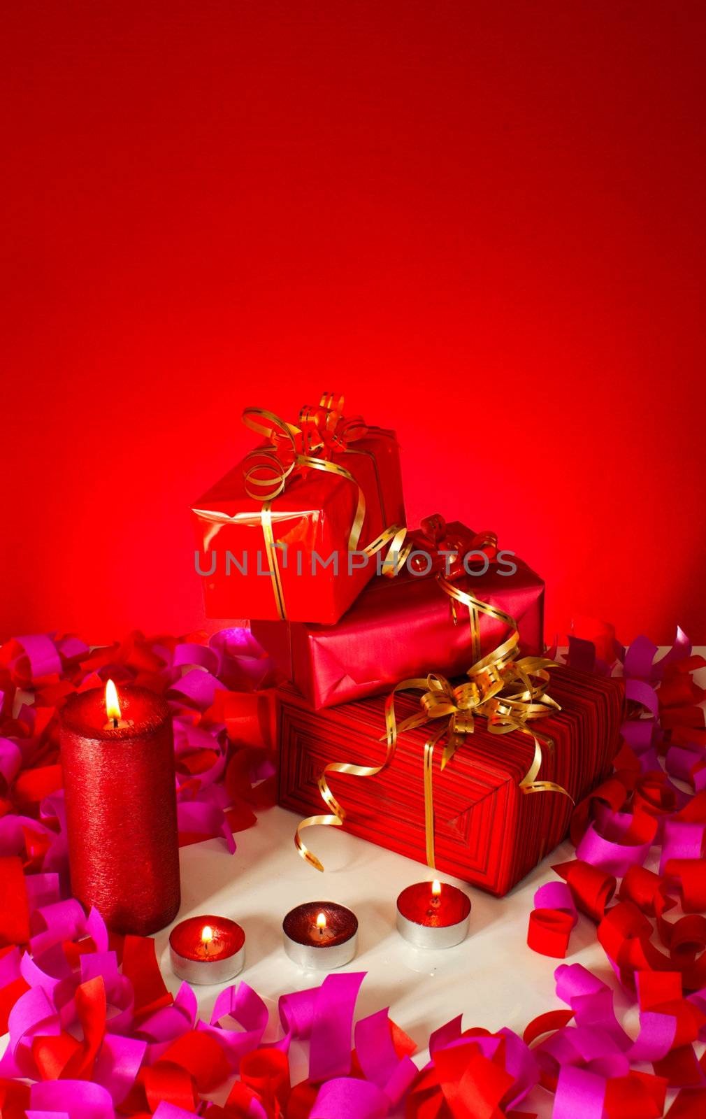 Christmas gifts and candles over red background