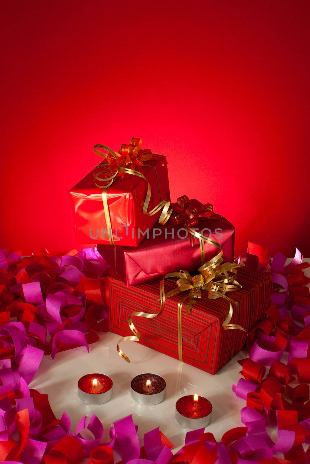 Christmas gifts and candles over red background