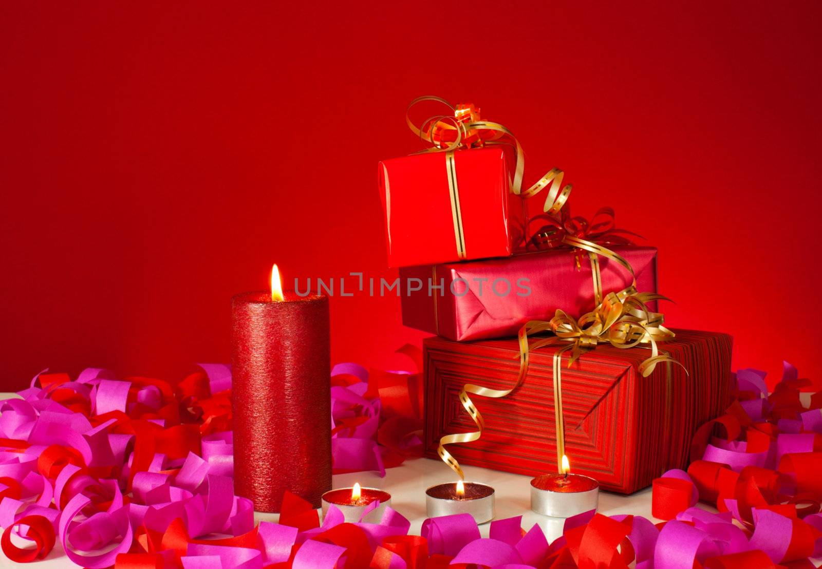 Christmas gifts and candles over red background