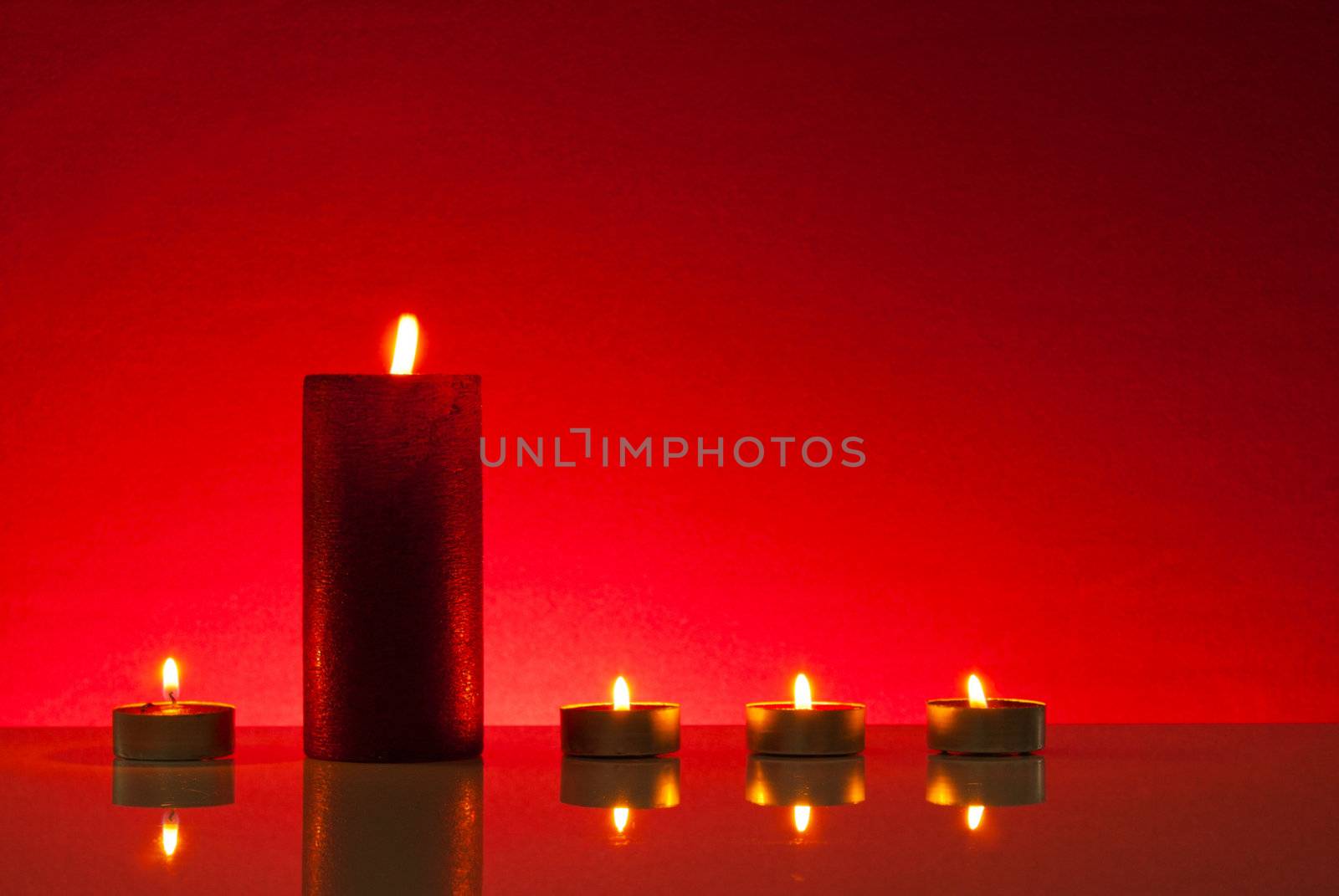 Four burning candles over red background