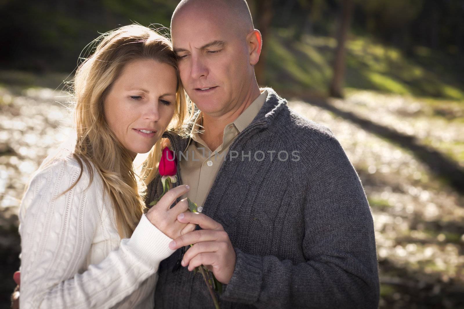 Attractive Young Couple Wearing Sweaters with a Rose in the Park.