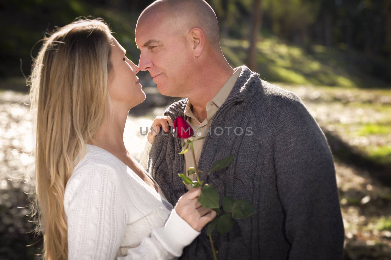 Attractive Young Couple Wearing Sweaters with a Rose in the Park.