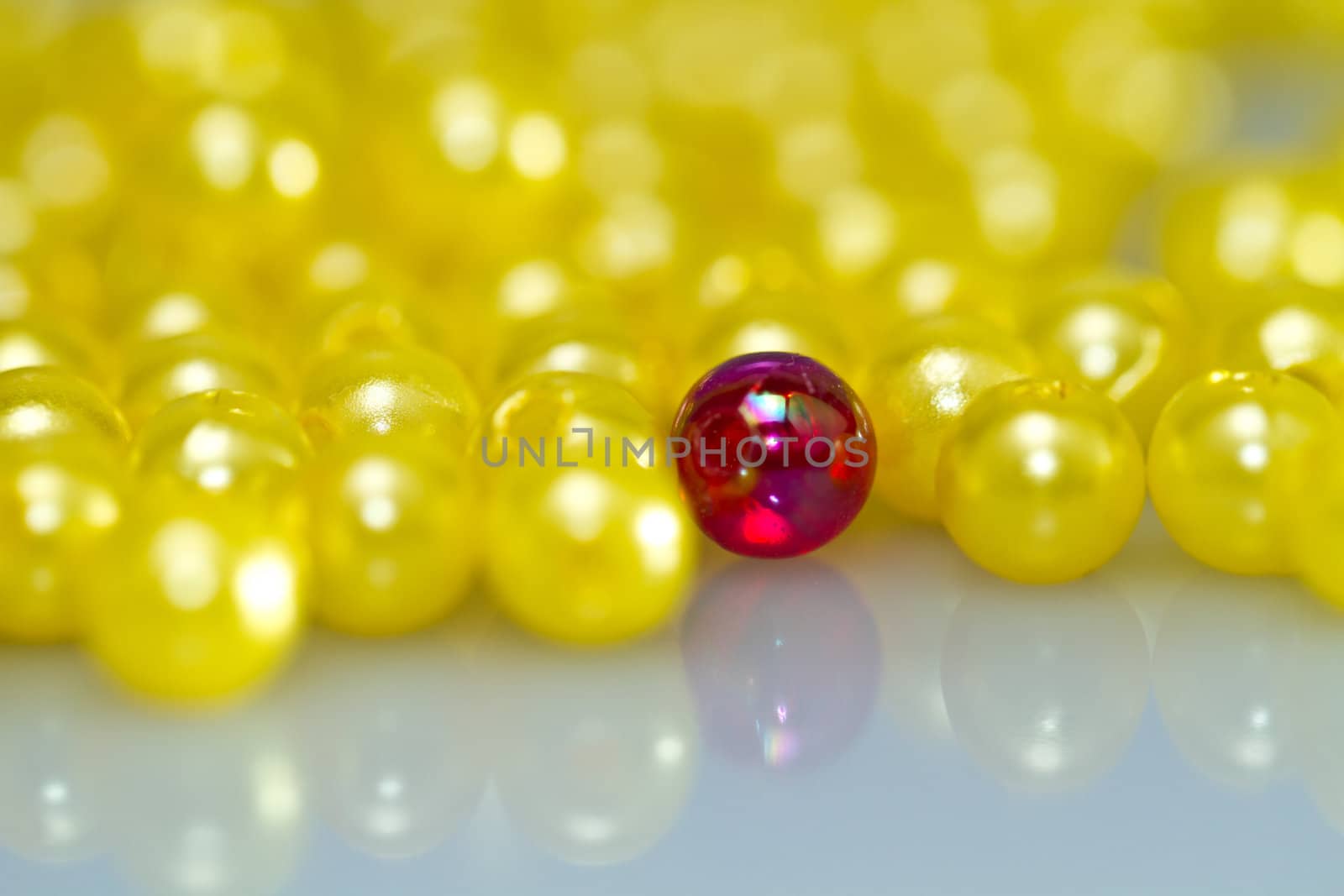 Close up of a red bead almost surrounded by yellow beads with shallow DOF, with mirror image in landscape orientation