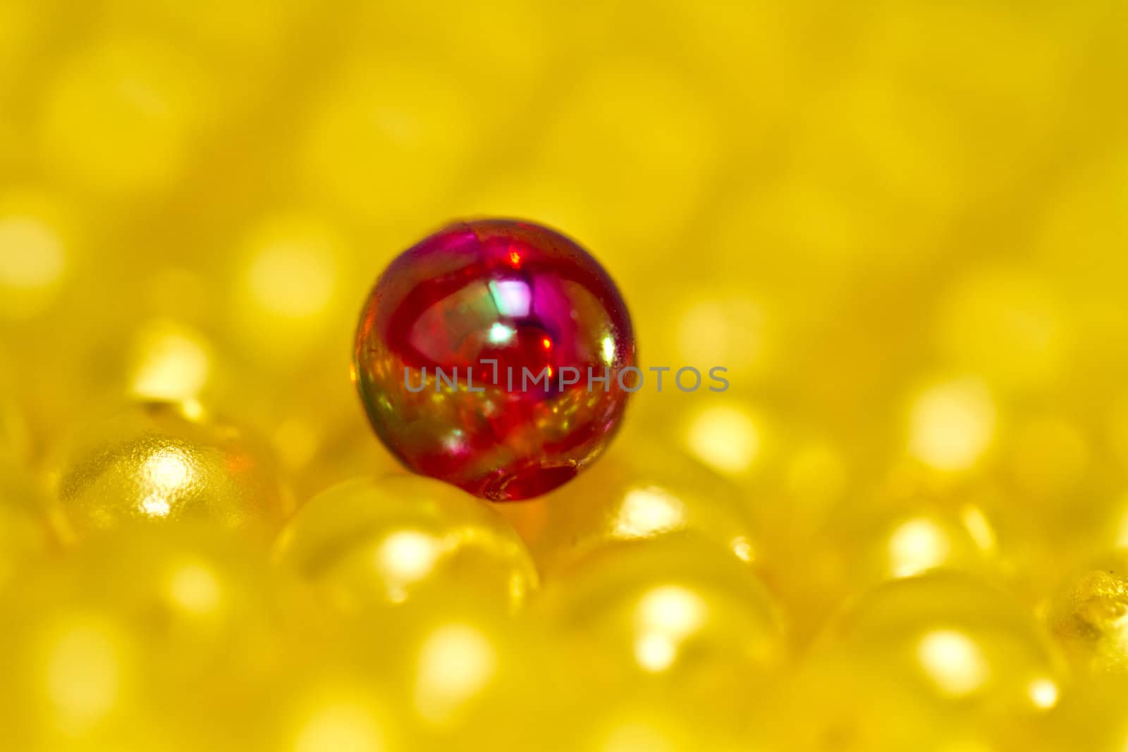 close up of a red bead on top of yellow beads with shallow DOF