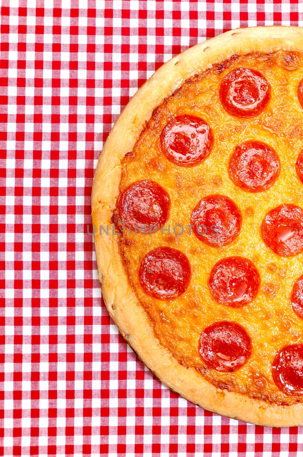 Pepperoni pizza half on red gingham tablecloth.
