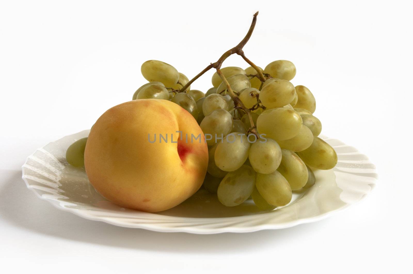 isolated grape and peach on white plate by Kuzma