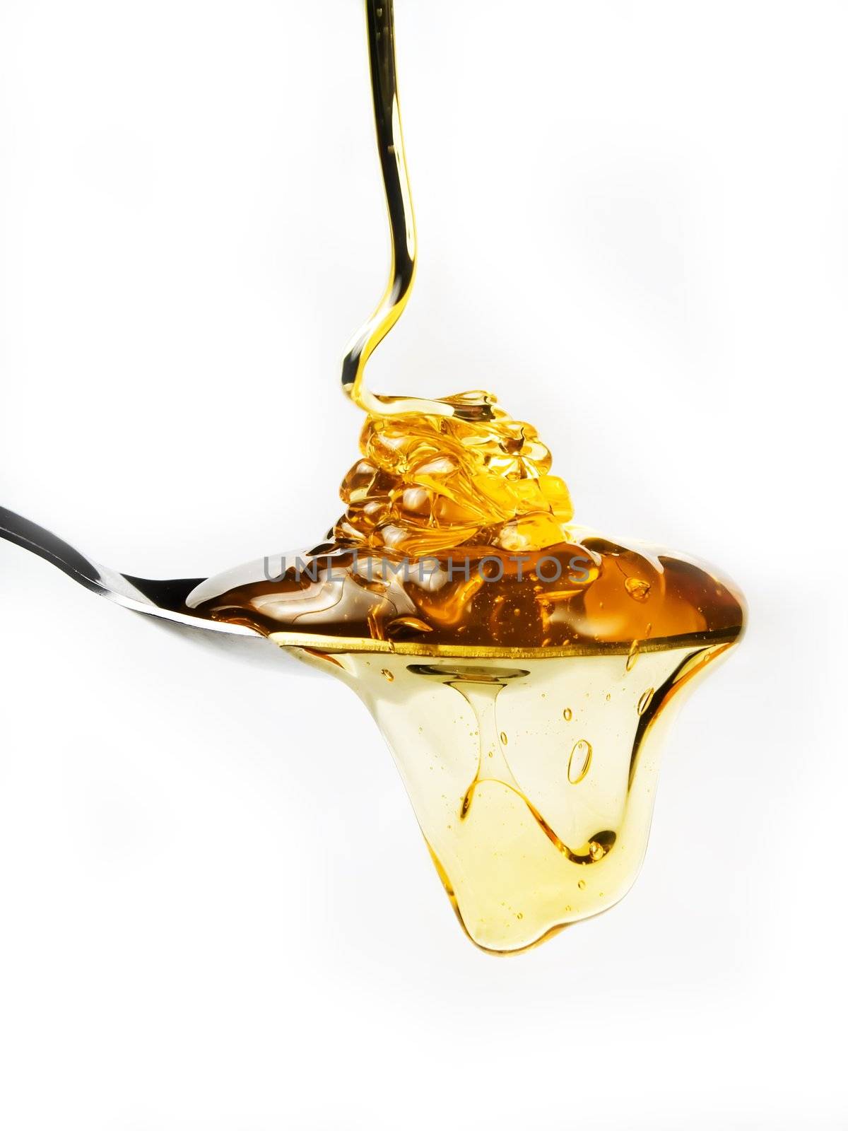 Honey on a spoon over a white background