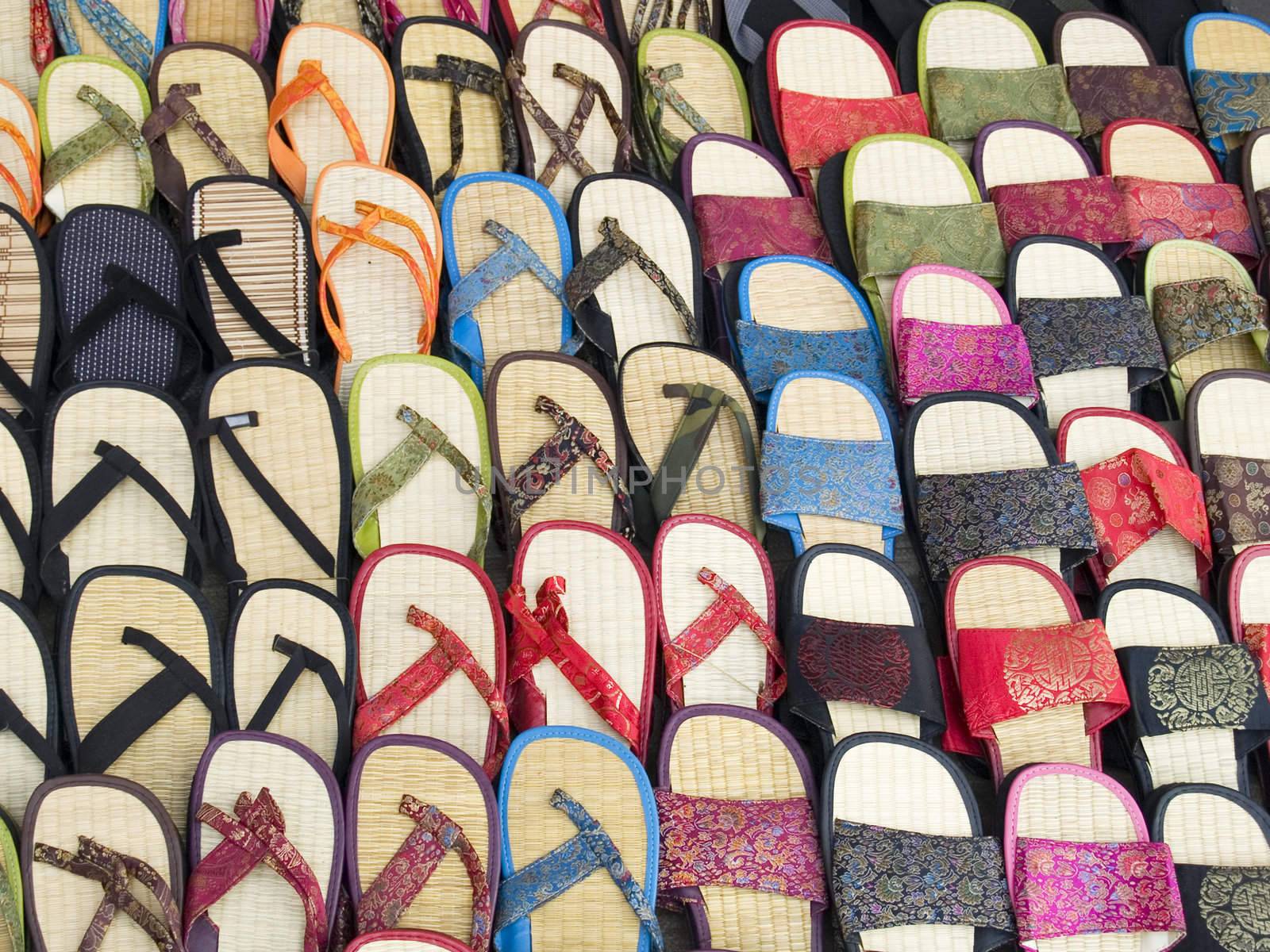 Lots of sandals in a market, many with Chinese style silk fabrics, all for the right foot.