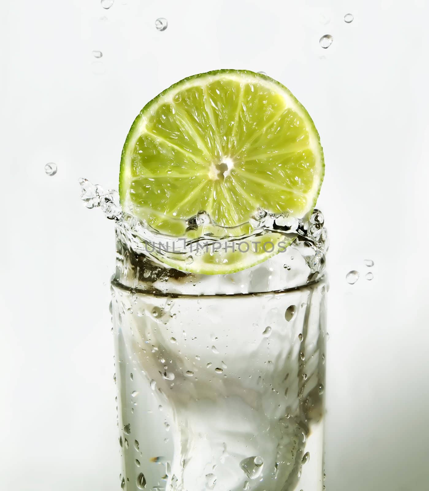 Lime slice falling in a glass of water