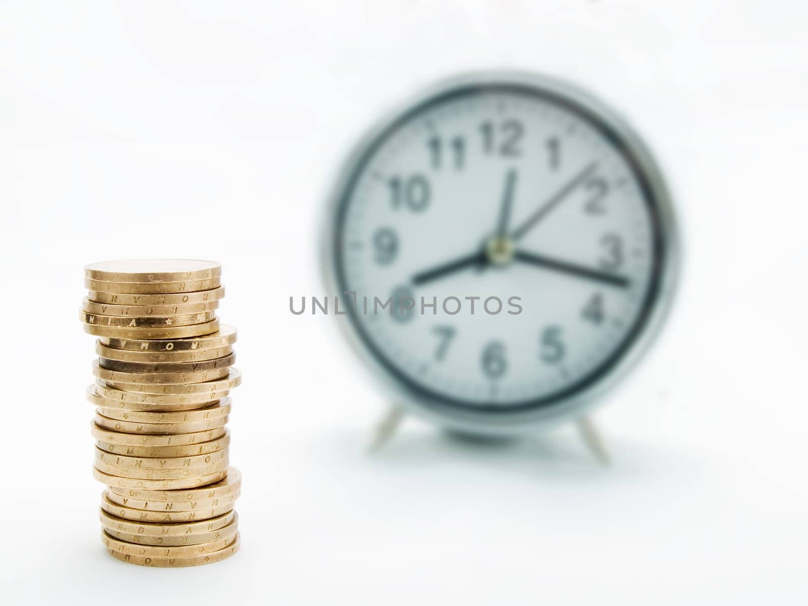 Pile of coins and alarm clock on a white background