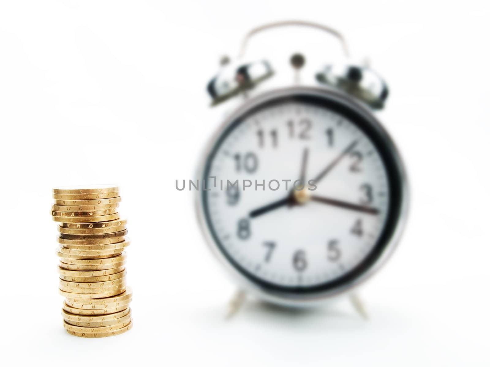 Pile of coins and alarm clock on a white background