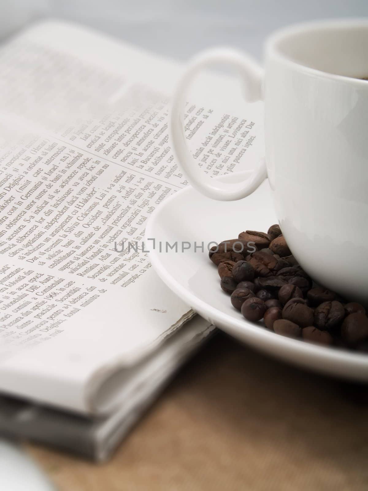 Coffee cup with coffee beans and a newspaper