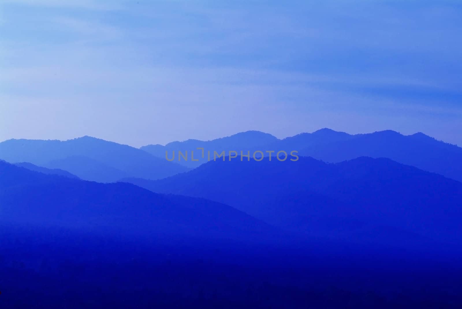 Abstract of mountains and hills at sunrise, in different shades of blue.