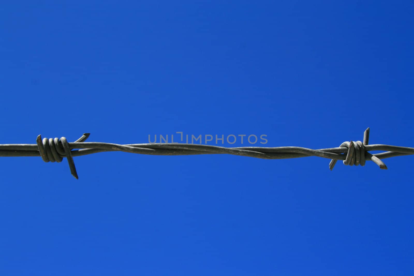 Close up of a barbed wire over blue sky.
