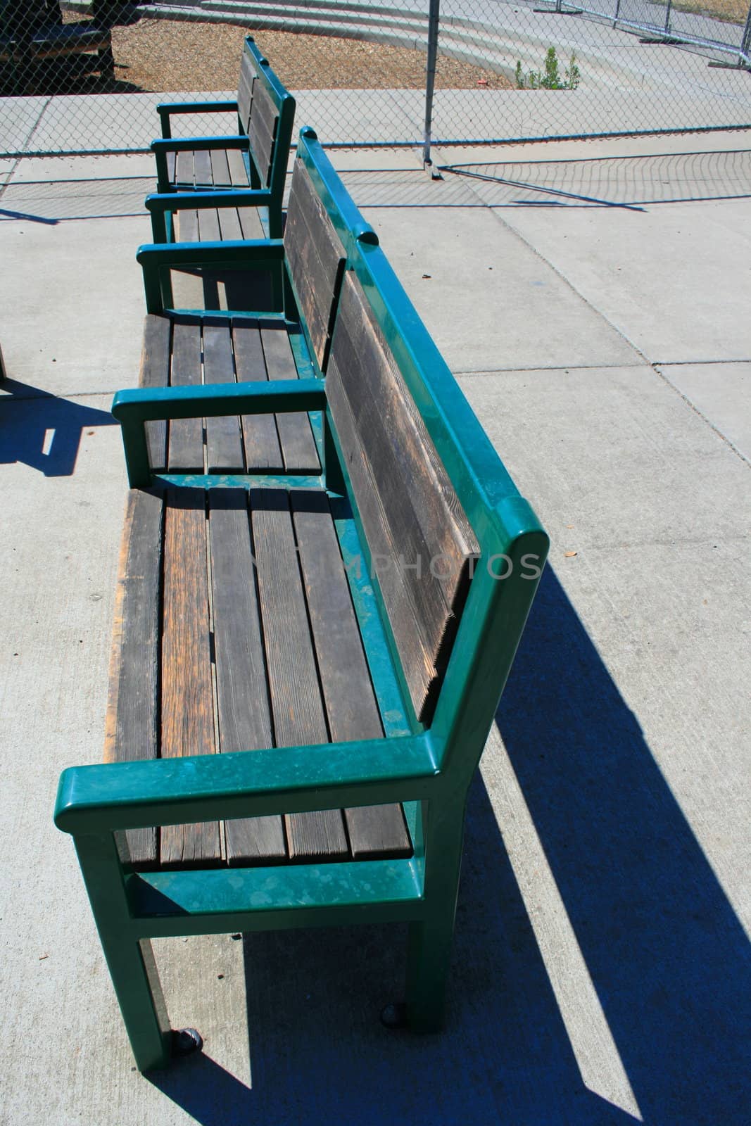 Close up of the two green benches in a park.
