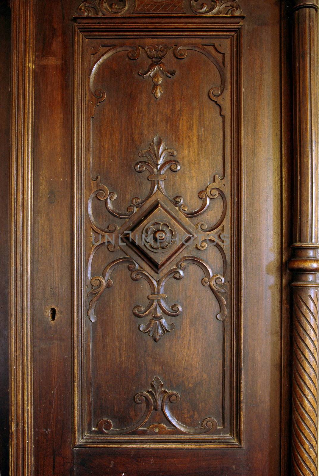 A picture of a wooden carved door of an antique closet