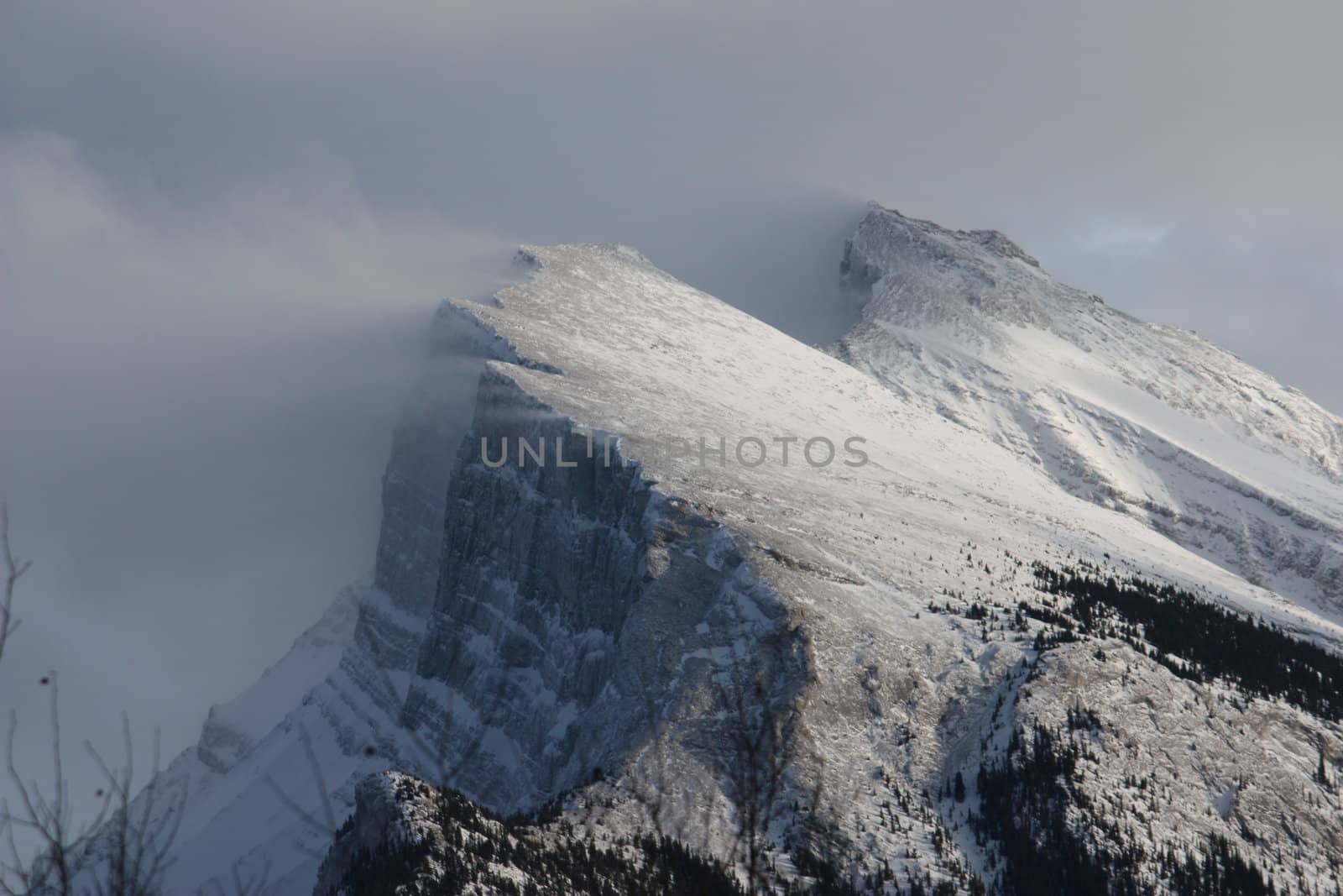 Snow streaming off a mountain peak by chrisga