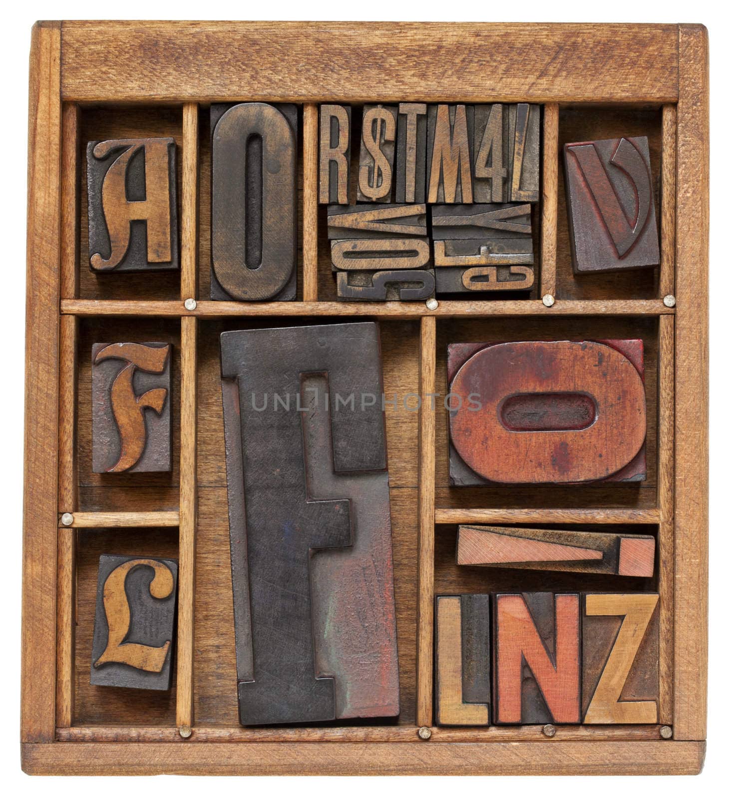a variety of vintage letterpress printing blocks with big letter F in a small wooden typesetter box with dividers, isolated on white