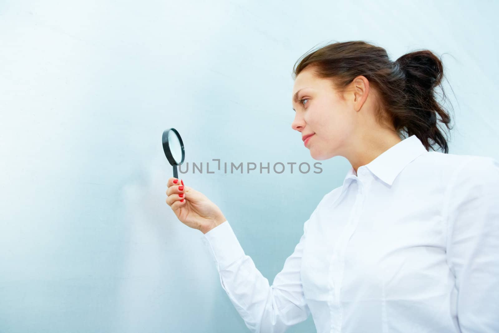 Young woman inspecting with magnifying glass outside building