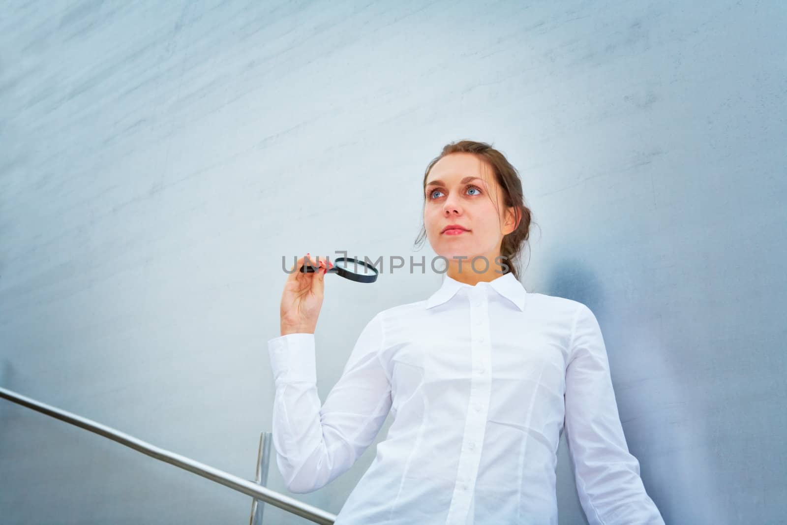 Young woman with magnifying glass outside building