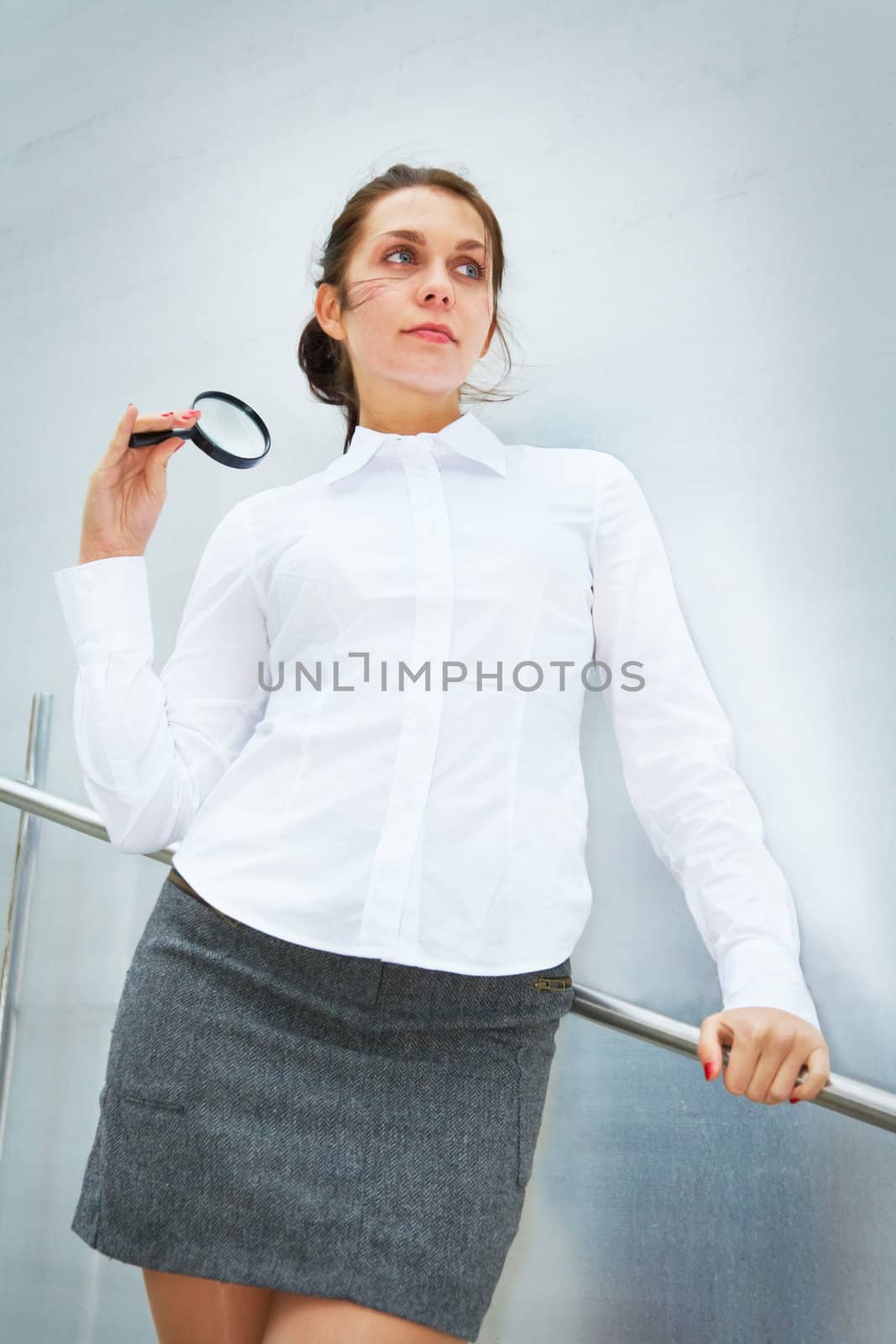 Young woman with magnifying glass beside wall