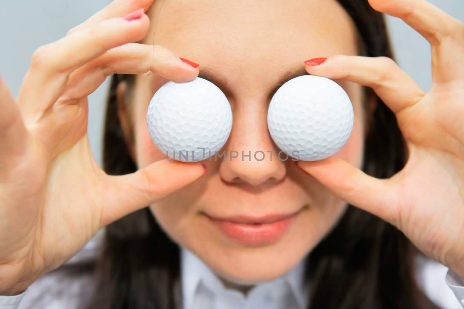 Close-up of woman holding golf balls over her eyes