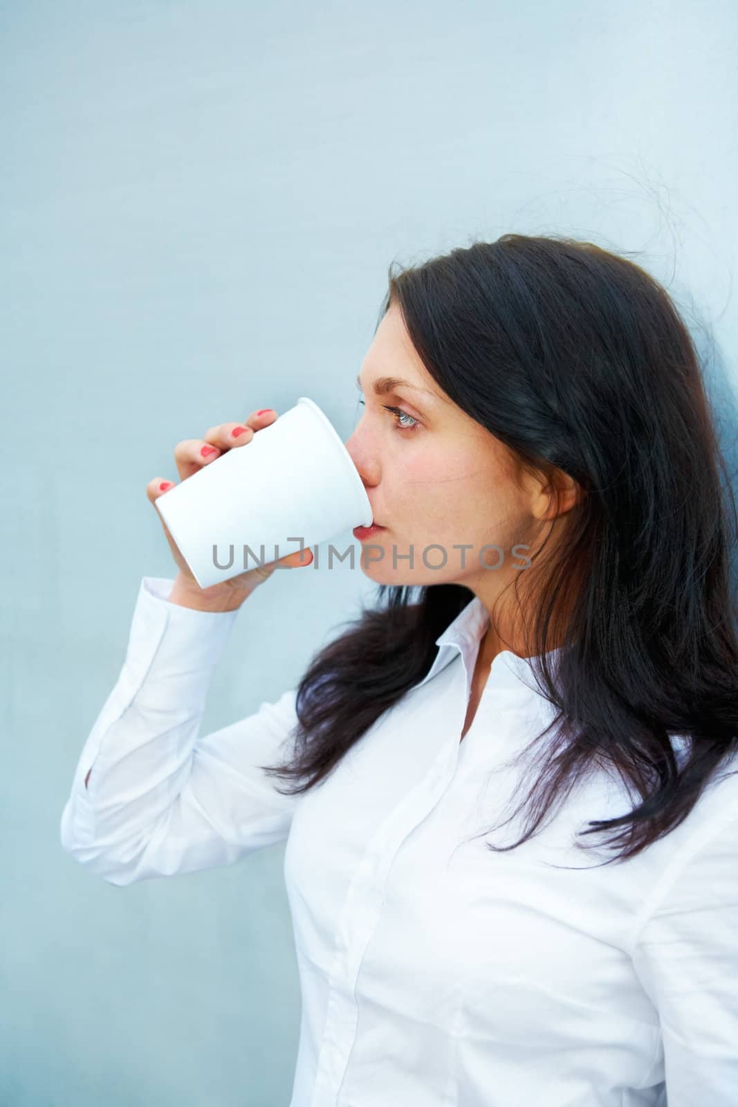 Young woman drinking coffee leaning to wall