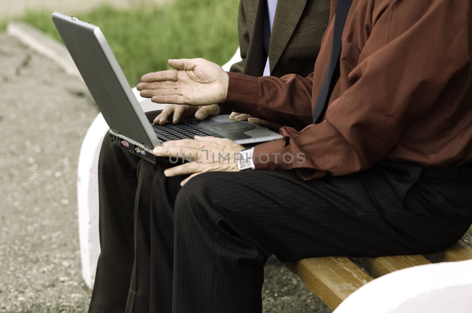 two businessmen with computer outside