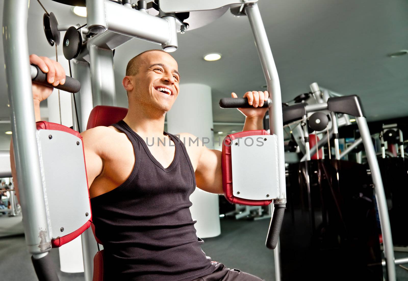 Athletic handsome male working out at the gym on butterfly machine