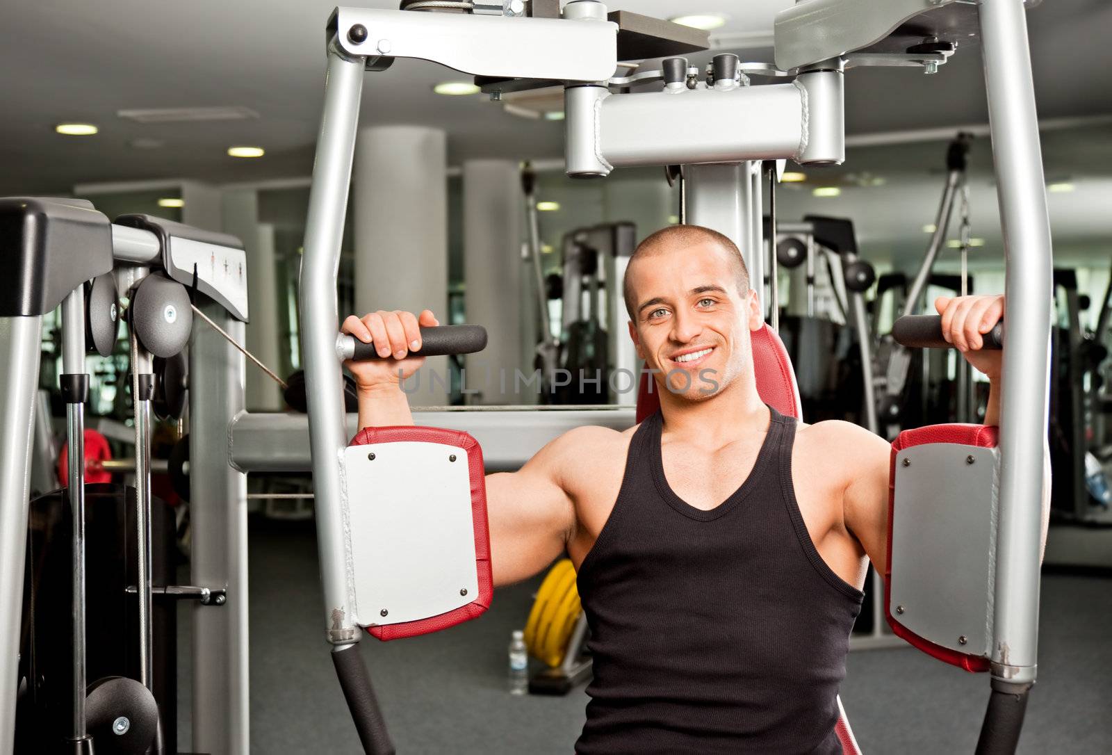 Athletic male doing fitness training on butterfly machine in gym