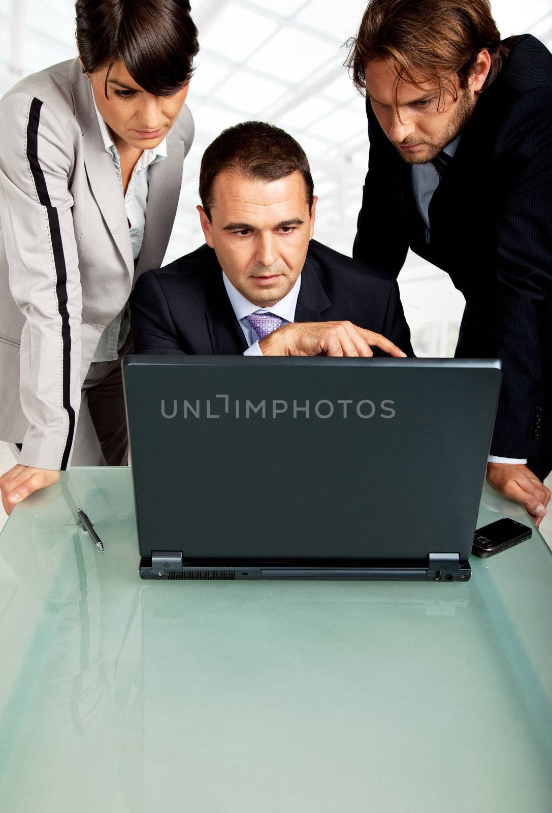 team of three business people , looking at the monitor of a laptop