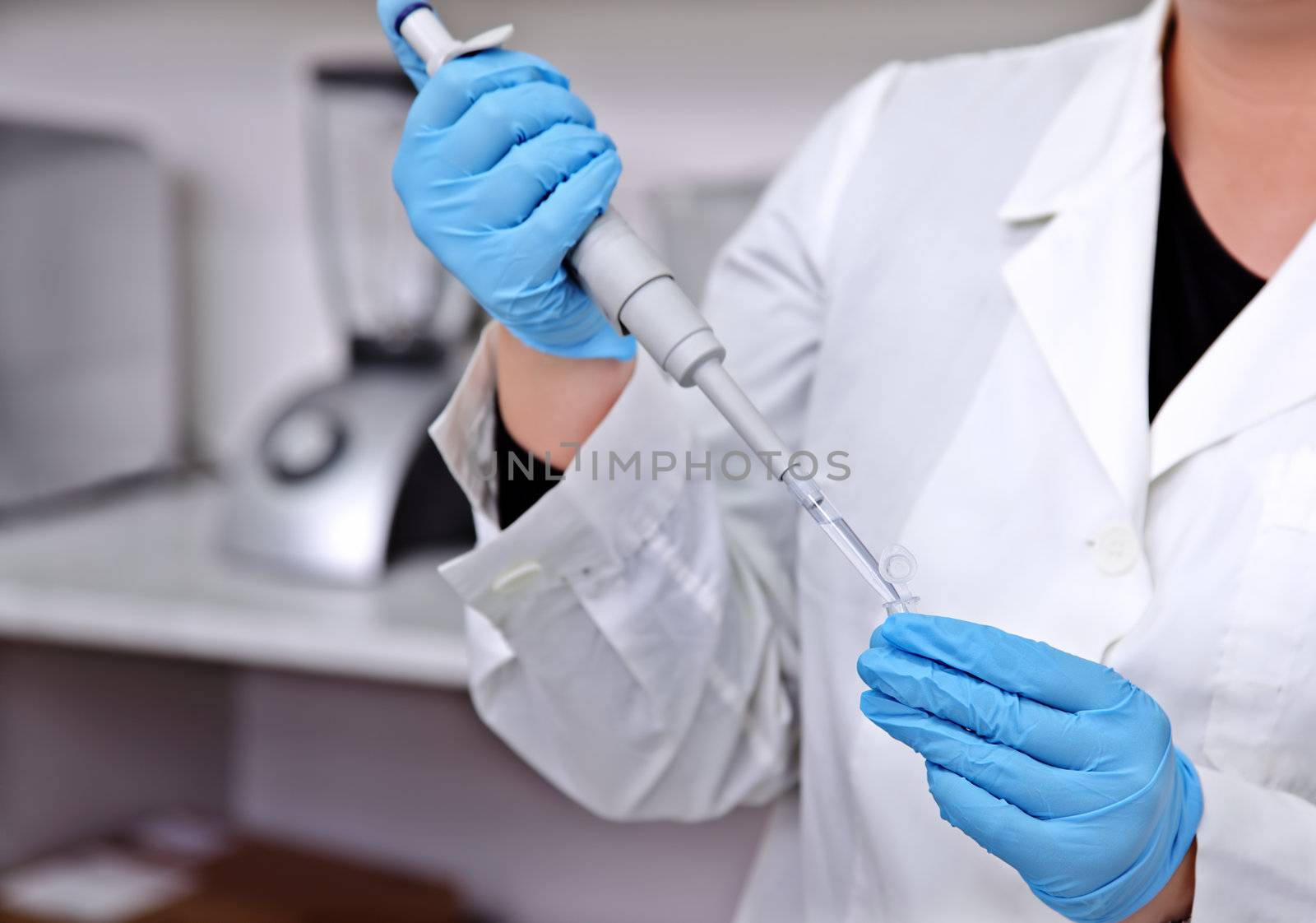 laboratory worker with protective gloves making test samples with pipette