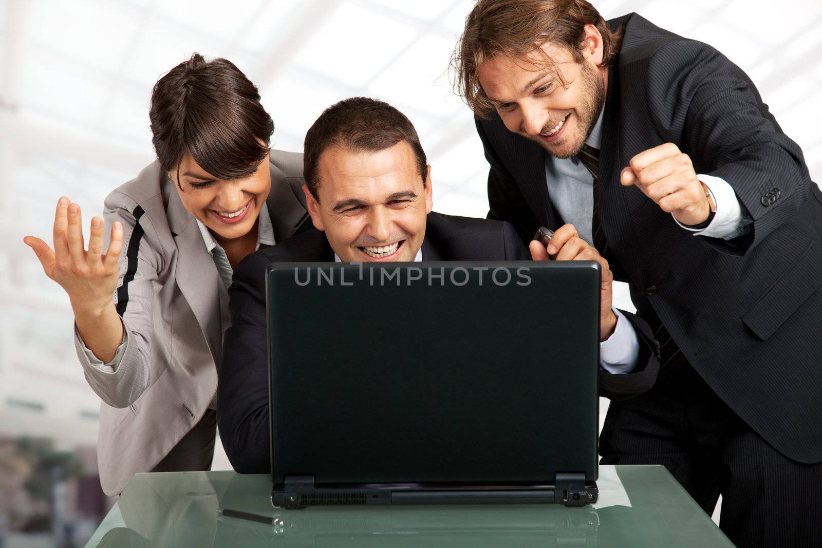 three businesspeople gesturing and smiling over a laptop