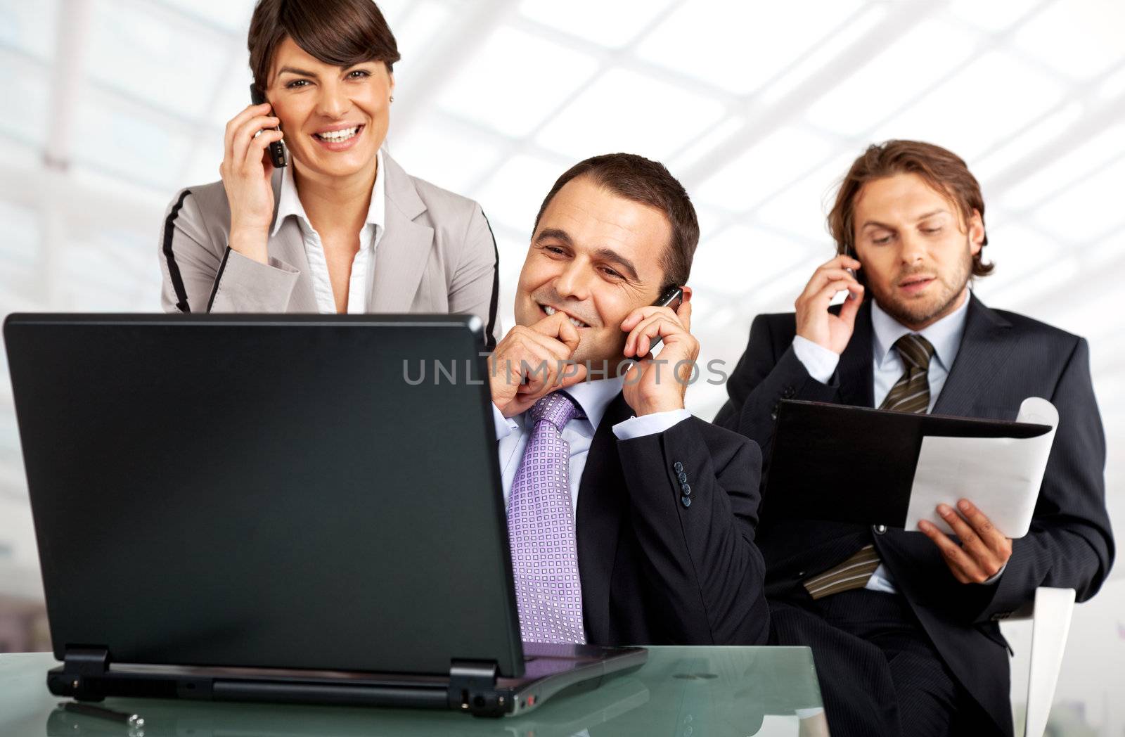 business team of three on their phones with a laptop