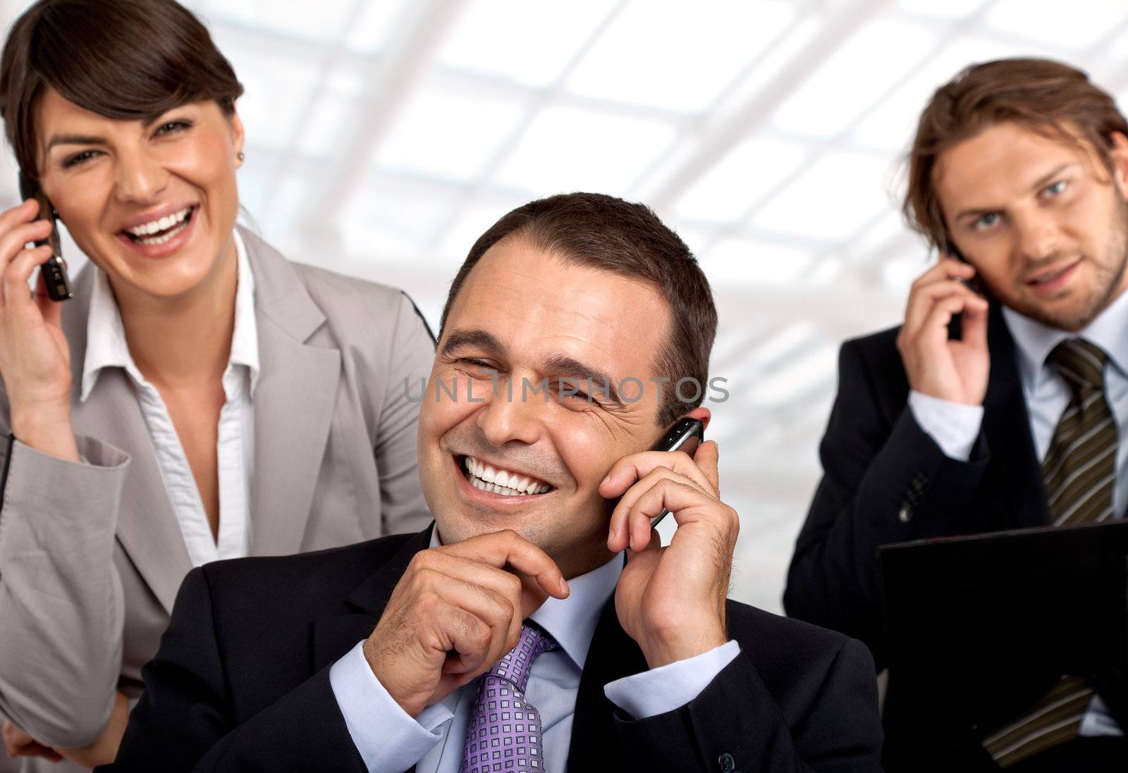 three happy business people talking on their cellular phones